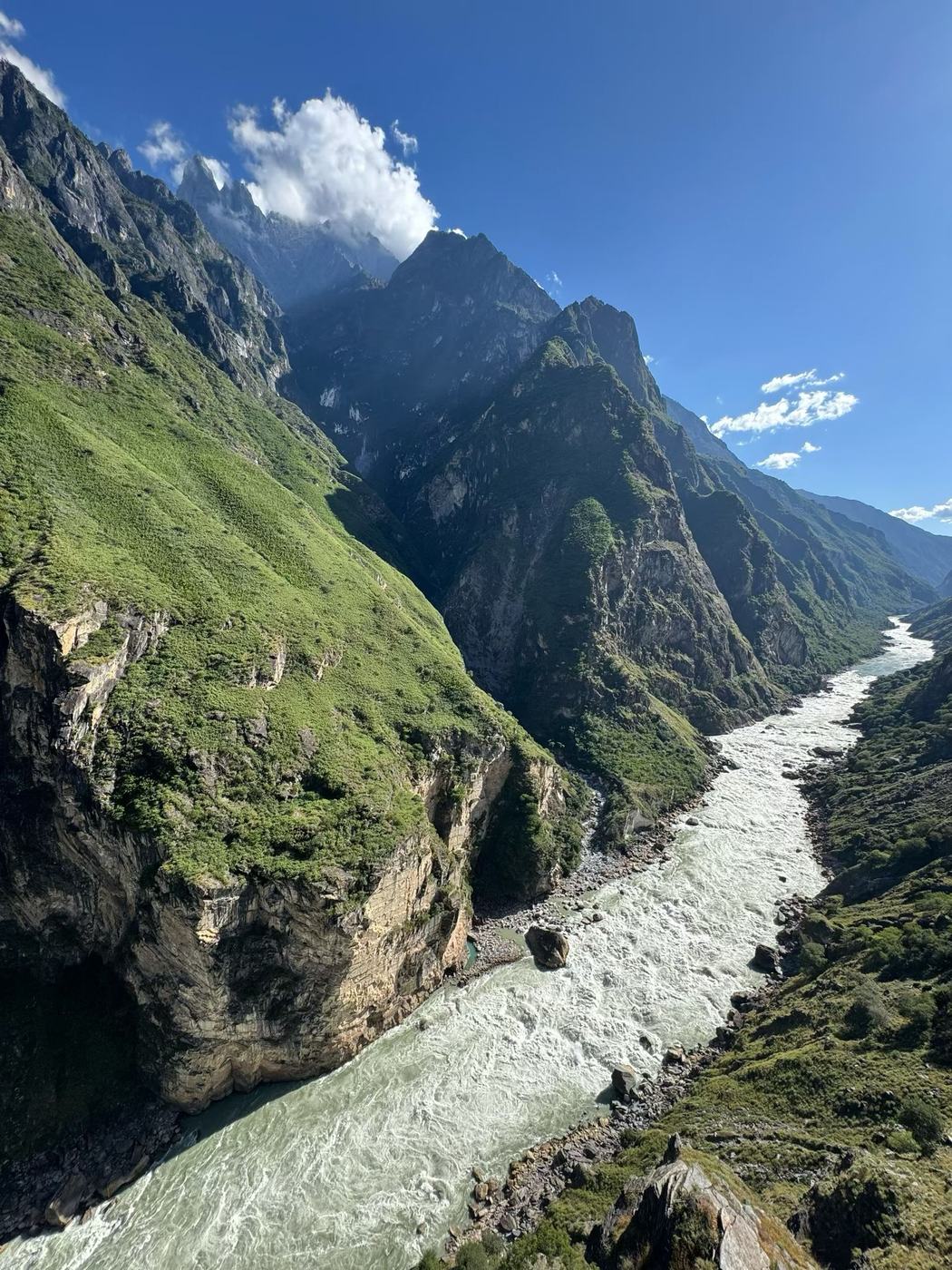 The river rushing through the gorge below steep green slopes, seen from the high trail