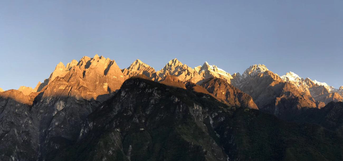 Panorama of the Jade Dragon range lit orange at sunset